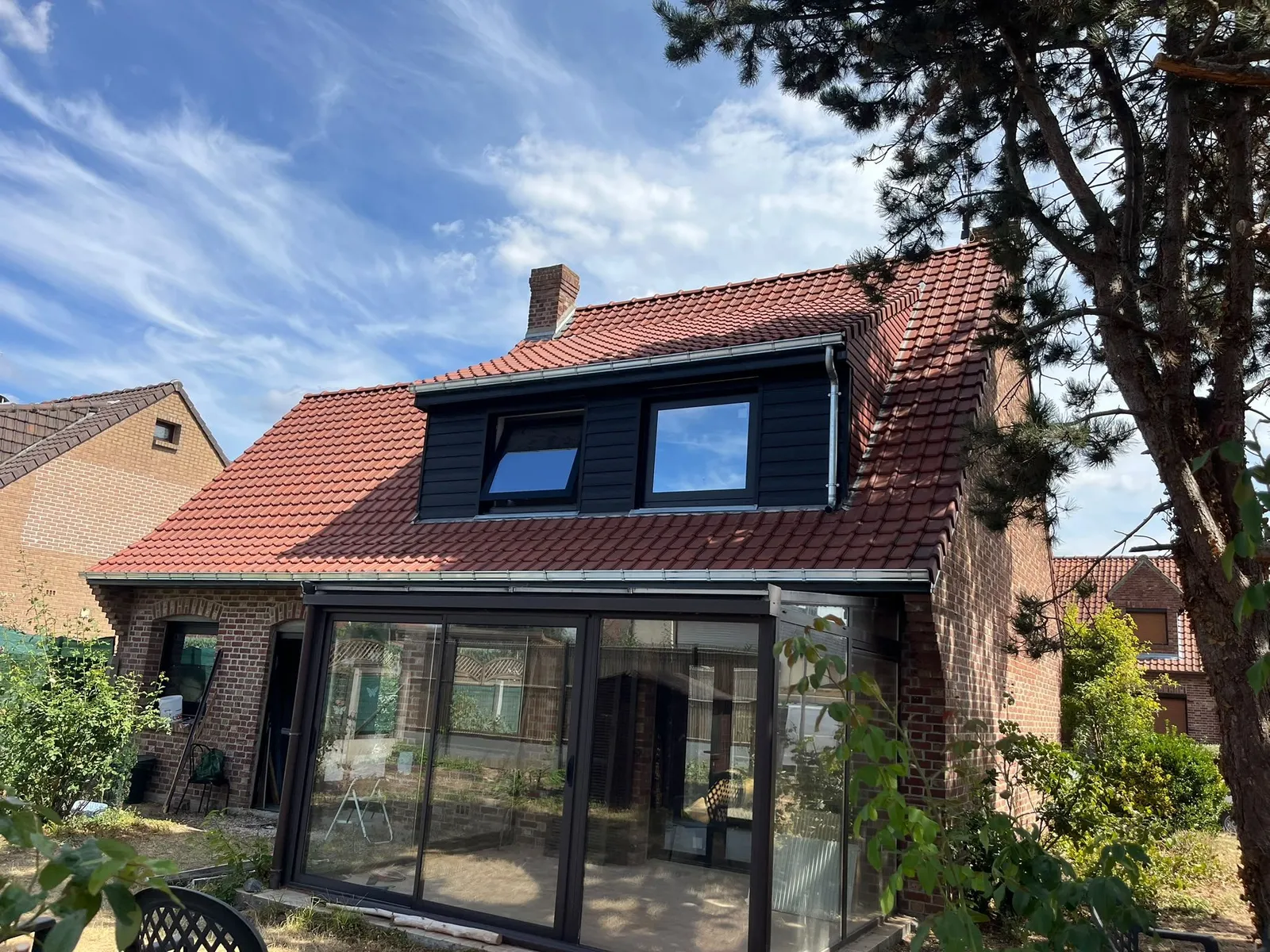 Arrière de la maison en brique avec toiture rénovée en tuiles rouges, lucarne noire et descente en zinc