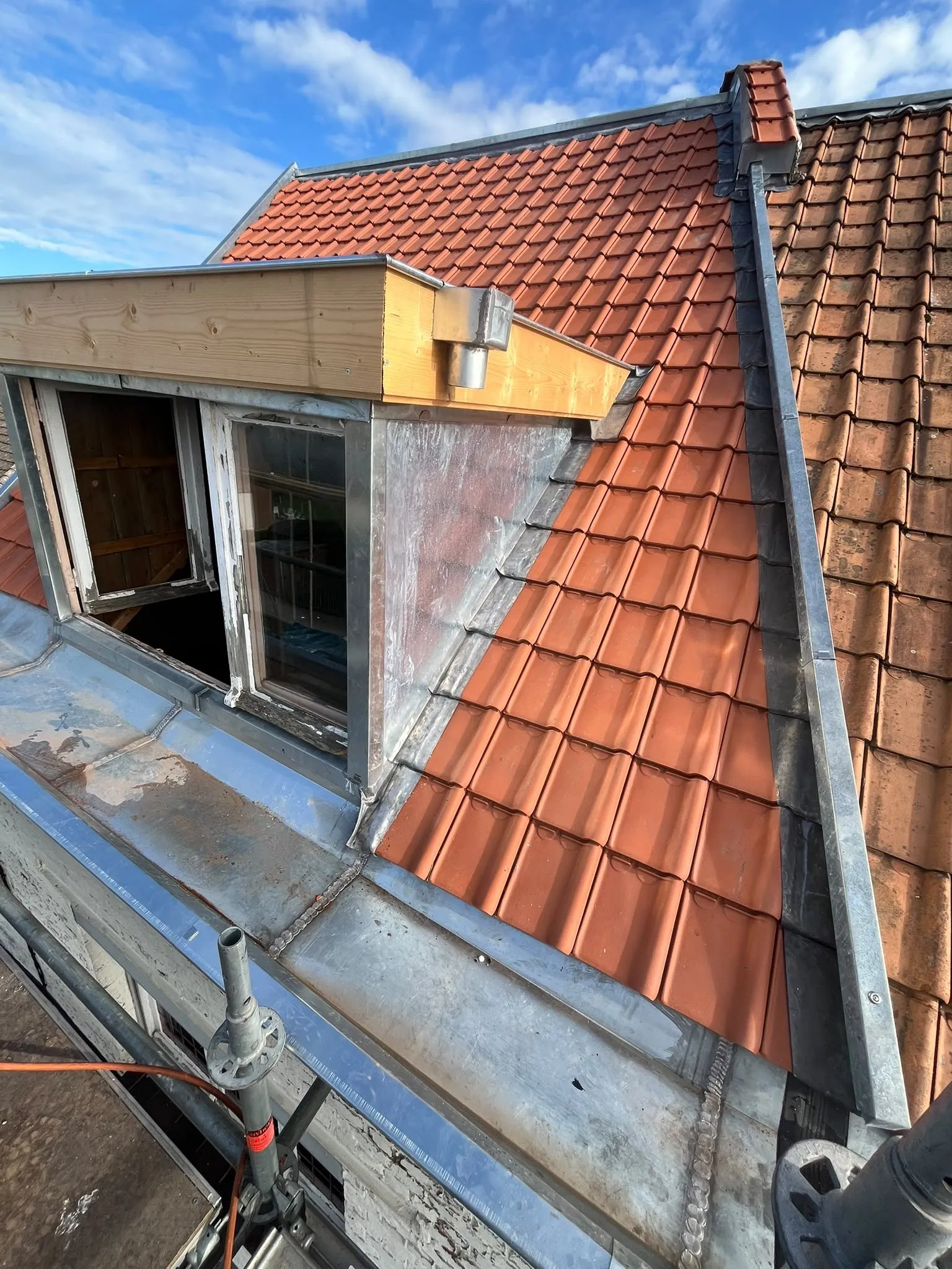 Lucarne habillée de zinc et pan de tuiles rouges neuves, avec chéneau en zinc et échafaudage